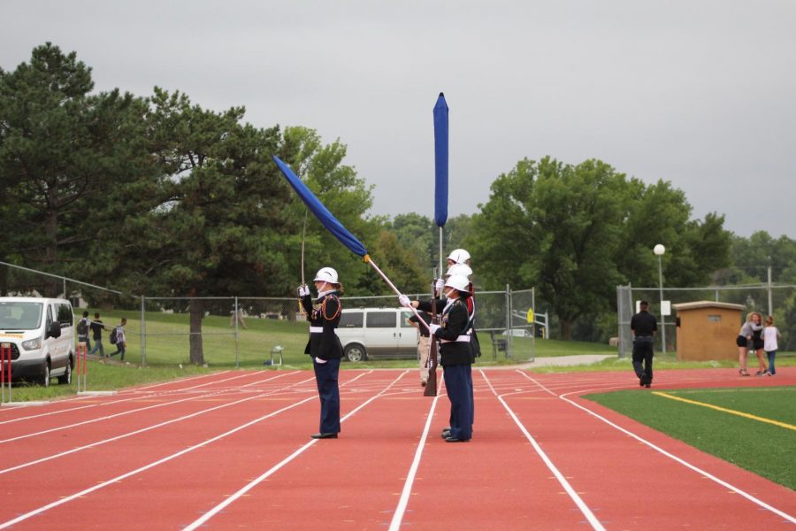 Omaha North High’s JROTC Color Gurad honors America during “The Star Spangled Banner.” The flags were covered becuase of the rain. 
Photo by Caitlin Pieters