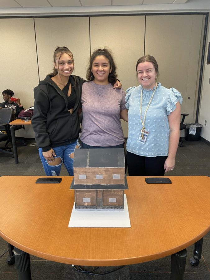 Destinee Anderson, 11, Samantha Mejia, 12, and Jessica Koch stand together around Mejia’s house project. The house was made in Koch’s engineering class.
